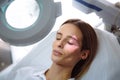 Close-up beautiful female face with vein scanner and cosmetologist`s hands with syringe during facial beauty injections Royalty Free Stock Photo