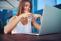 Close-up of beautiful female in open air cafÃÂ© watching something on her laptop and holding a cup of coffee Royalty Free Stock Photo