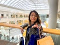 Close up of beautiful female standing in shopping center with many paper bags in hands and smiling looking at camera Royalty Free Stock Photo