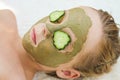 Close up of beautiful girl with facial mask of cucumber and clay