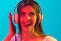 Close up beautiful girl in headphones isolated on blue background in neon light Royalty Free Stock Photo