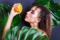 Close-up of beautiful girl posing in tropical forest. Portrait of beautiful African American woman with tropical fruits Royalty Free Stock Photo