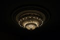 Close-up of a beautiful large crystal chandelier of round shape hanging from the ceiling in the interior against a dark background Royalty Free Stock Photo