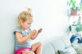 Close up Beautiful little baby girl holding and playing with smart phone on the white wall background. Children and technology con Royalty Free Stock Photo