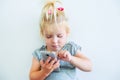 Close up Beautiful little baby girl holding and playing with smart phone on the white wall background. Children and technology con Royalty Free Stock Photo