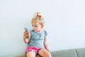 Close up Beautiful little baby girl holding and playing with smartp hone sitting on the sofa on the white wall background. Childre Royalty Free Stock Photo