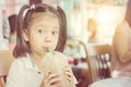 Close up of beautiful little cute girl drinking iced chocolate in coffee shop Royalty Free Stock Photo