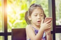 Close up of beautiful little cute girl looking up thinking and holding smartphone, Happy kid concept Royalty Free Stock Photo