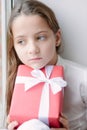 Pretty little girl dreaming by the window holding gift Royalty Free Stock Photo