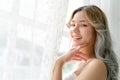 Close up of Beautiful lovely Asian woman looking at camera and standing near a window white curtains in bedroom in early morning Royalty Free Stock Photo