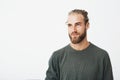 Close up of beautiful manly guy with light hair, fashionable hair and beard in grey shirt smiling and looking aside with Royalty Free Stock Photo