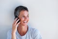 Close up beautiful middle age woman smiling and talking on mobile phone against white wall Royalty Free Stock Photo
