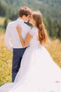 Close-up of beautiful pair holding each other outdoors at sunny day with forest as background