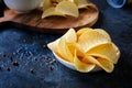 Close-up of beautiful potato chips and sauce in a white bowl on a wooden cutting board. Royalty Free Stock Photo