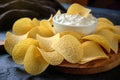 Close-up of beautiful potato chips and sauce in a white bowl on a wooden cutting board Royalty Free Stock Photo