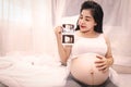 Close-up of a beautiful pregnant woman holding an ultrasound scan. A pregnant Asian woman is smiling holding an ultrasound image Royalty Free Stock Photo