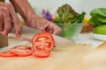 Close-up beautiful round red tomato on cutting board, Man cooking in kitchen during holidays who doesn't want go out eat, Royalty Free Stock Photo