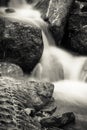 Close up of beautiful silky soft river waterfalls flowing in autumn scenery forest with dead leaves in black and white, france Royalty Free Stock Photo