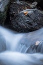 Close up of beautiful silky soft river waterfalls flowing in autumn scenery forest with dead leaves Royalty Free Stock Photo