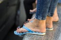 Close up of beautiful slim legs of young girl in blue jeans barefooted in rubber sandals with bright painted red nails standing on Royalty Free Stock Photo