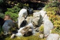 Close up of a beautiful stream with small rocky waterfalls lined by shrubs and plants in The Friendship Garden