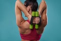 Close-up of a beautiful strong muscular back of a toned woman holding dumbbells and pumping triceps muscles. Healthy lifestyle
