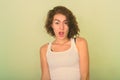 Close up of beautiful teenage girl looking shocked against green painted wall Royalty Free Stock Photo