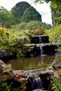 A close up of a beautiful waterfall that runs through a garden.