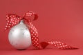 Close up of beautiful white Christmas tree ornament with red polka dot ribbon on red background