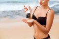 Close up beautiful woman in bikini applying sun cream on hands. Sun protection. Skin care. Girl using sunscreen to skin Royalty Free Stock Photo