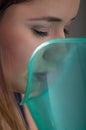 Close up of a beautiful woman doing inhalation with a vaporizer nebulizer machine on grey background