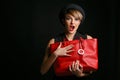 Close up of a beautiful woman with a good sense of humor , holding her fancy red bag.