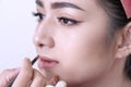 Close up beautiful woman with hands beautician or makeup artist applying lipstick on her face in studio Royalty Free Stock Photo