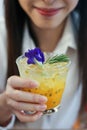 Close up a beautiful woman with Passion fruit juice iced in a glass on wooden table in cafe