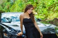 Close up of beautiful woman wearing a black dress and a red flower in her head and posing in front of a luxury black car Royalty Free Stock Photo