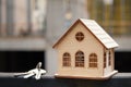 Close-up of a beautiful wooden toy house with a bunch of keys against the background of the construction of a new residential