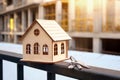 Close-up of a beautiful wooden toy house with a bunch of keys against the background of the construction of a new residential