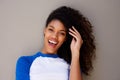 Close up beautiful young african american woman smiling with hand in hair against gray wall Royalty Free Stock Photo