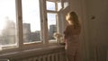 Close-up of beautiful young blonde woman in beige cotton night lingerie walking towards the window in her appartments Royalty Free Stock Photo