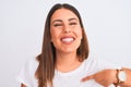 Close up of beautiful and young brunette woman standing over isolated white background with surprise face pointing finger to Royalty Free Stock Photo