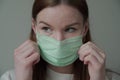 Close up of a beautiful young girl with long red hair in a medical mask. Orvi, coronovirus, acute respiratory infections.