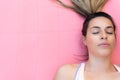 Close-up of a beautiful young girl meditating on a pink mat. The girl is wearing a ponytail and her eyes are closed.