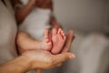 Close-up. Beautiful young mother holds in her hands the legs of the baby. Beautiful young mother plays with the baby in bed. Royalty Free Stock Photo