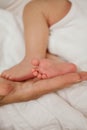 Close-up. Beautiful young mother holds in her hands the legs of the baby. Beautiful young mother plays with the baby in bed. Royalty Free Stock Photo