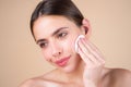 Close up beautiful young woman with cotton pad removing makeup. Skin care. Studio portrait of girl cleaning her face Royalty Free Stock Photo