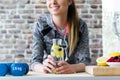 Beautiful young woman drinking lemon and berries juice in the kitchen at home.