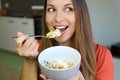 Close up of beautiful young woman eating skyr yogurt with cereal muesli fruit at home, looking to the side, focus on the model Royalty Free Stock Photo