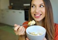 Close up of beautiful young woman eating skyr yogurt with cereal muesli fruit at home, looking to the side, focus on the model Royalty Free Stock Photo