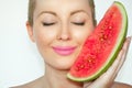 Close-up, beautiful young woman holding a watermelon face, eyes closed and gracious smile.