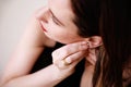 Close-up of beautiful young woman puts on diamond earring. Beauty model girl in jewellery, perfect face closeup. Royalty Free Stock Photo